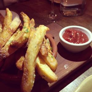 Photo of garlic seasoned french fries next to ketchup dipping sauce.