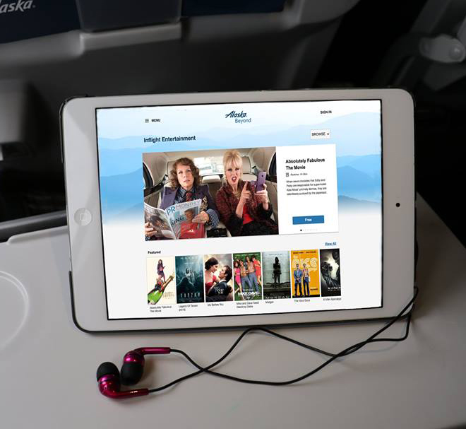 This is a photo of an Apple iPad sitting on an aircraft tray table using the Alaska