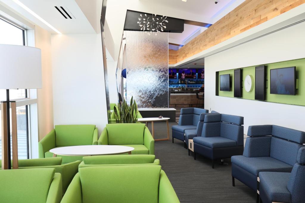 This is a photo of the new Alaska Lounge with green and navy seats, flatscreen TVs and a glass wall.