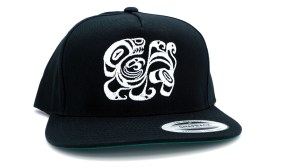 This is a photo of a black men's snap back style hat featuring a white Alaska Native contemporary design by Trickster Co.