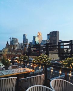 This is a photo of a rooftop cocktail bar overlooking the Minneapolis skyline in the evening light.