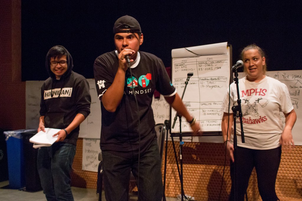 This is a photo of a group of three students rapping on a practice stage.