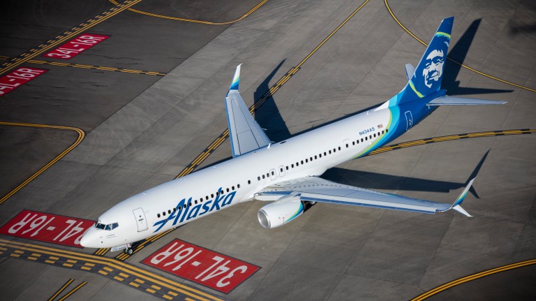 This is a photo of an Alaska Airlines jet taxiing on a runway.