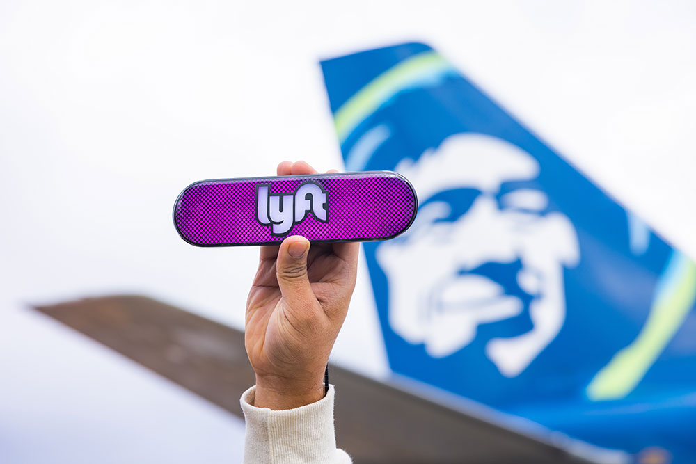 a hand holding a purple rectangular object with a blue and white airplane in the background