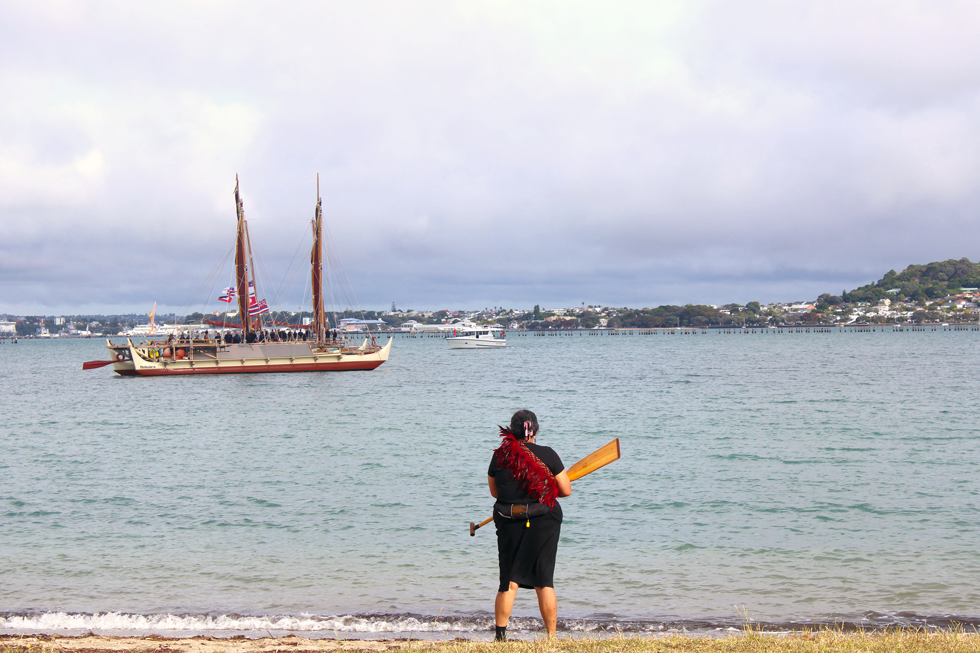 Maori woman on the shore looking out at canoe