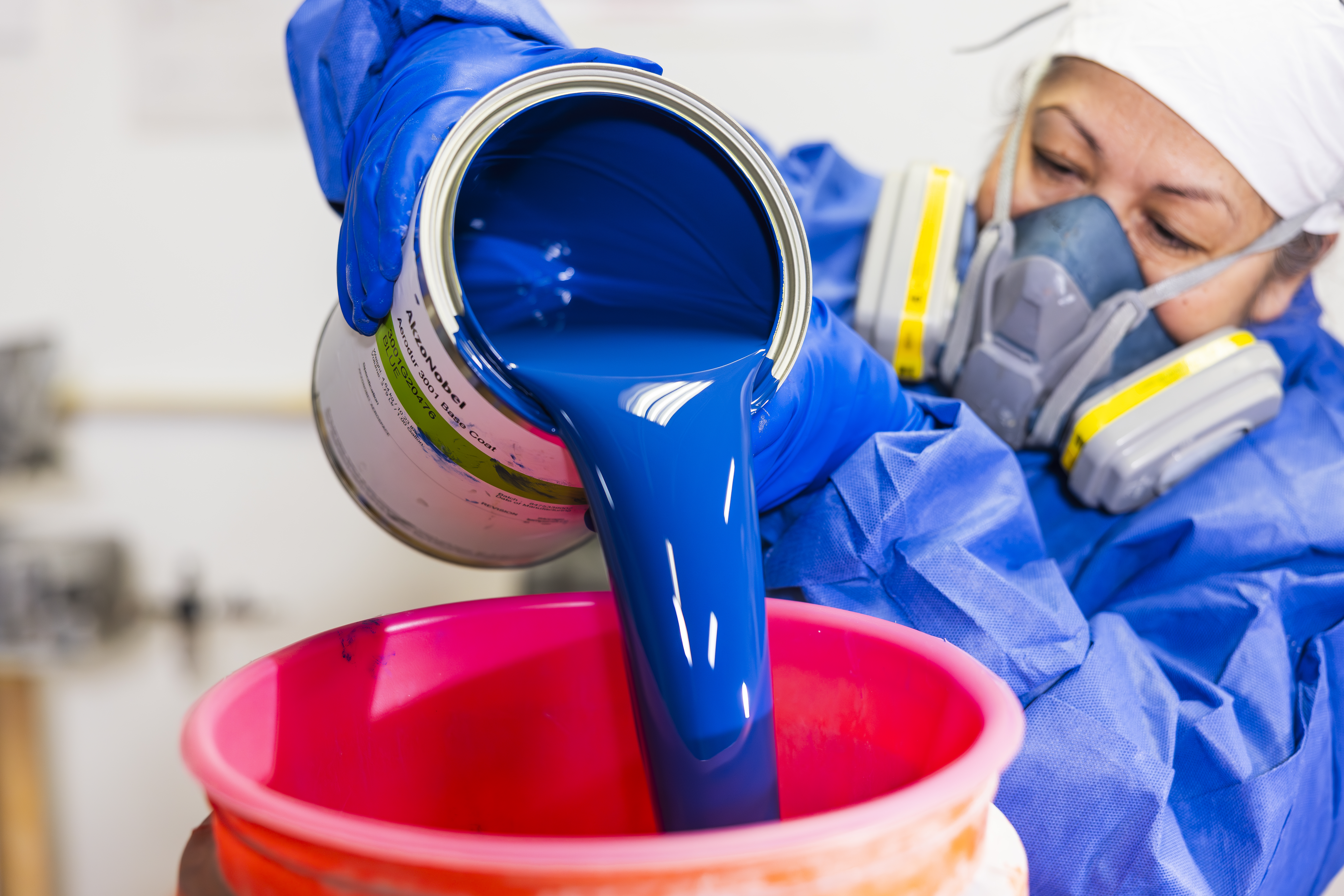 woman pouring blue paint into bucket