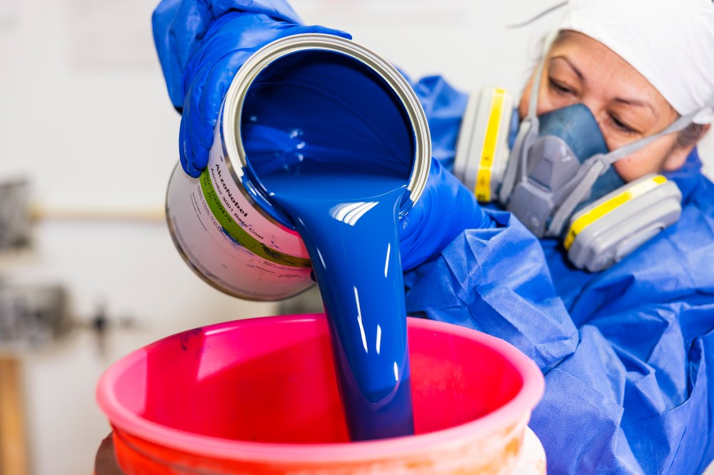 woman pouring blue paint into bucket