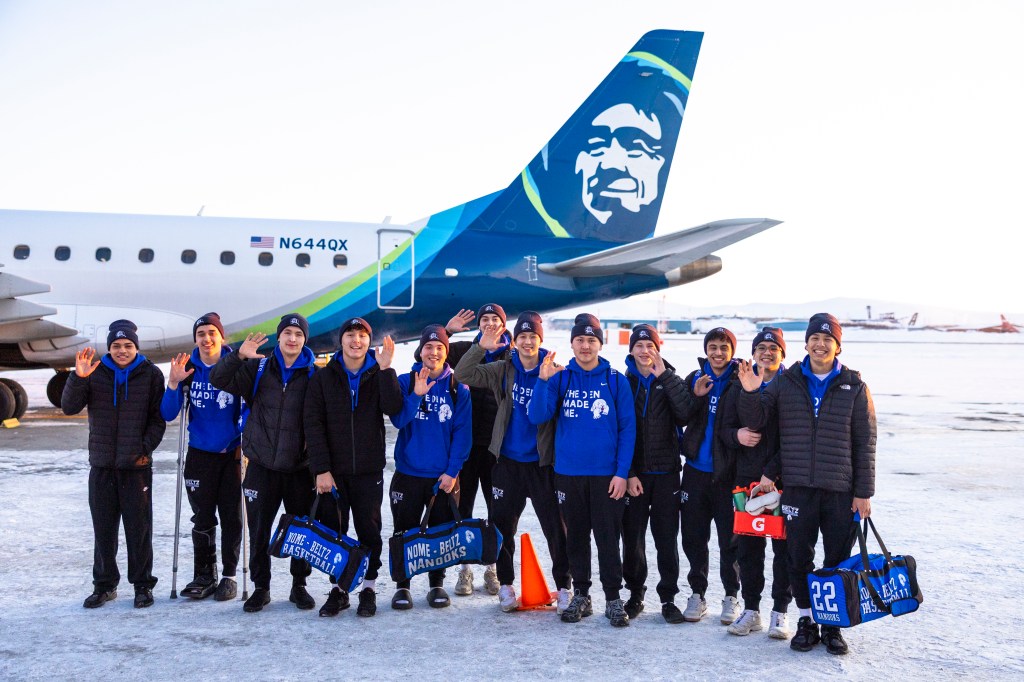 Nome basketball team in front of Alaska Airlines aircraft tail